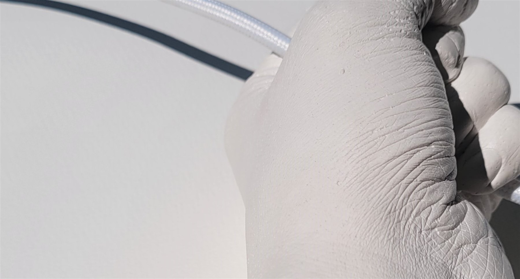 Wassertropfen auf einem Gipsarm im Gegenlicht