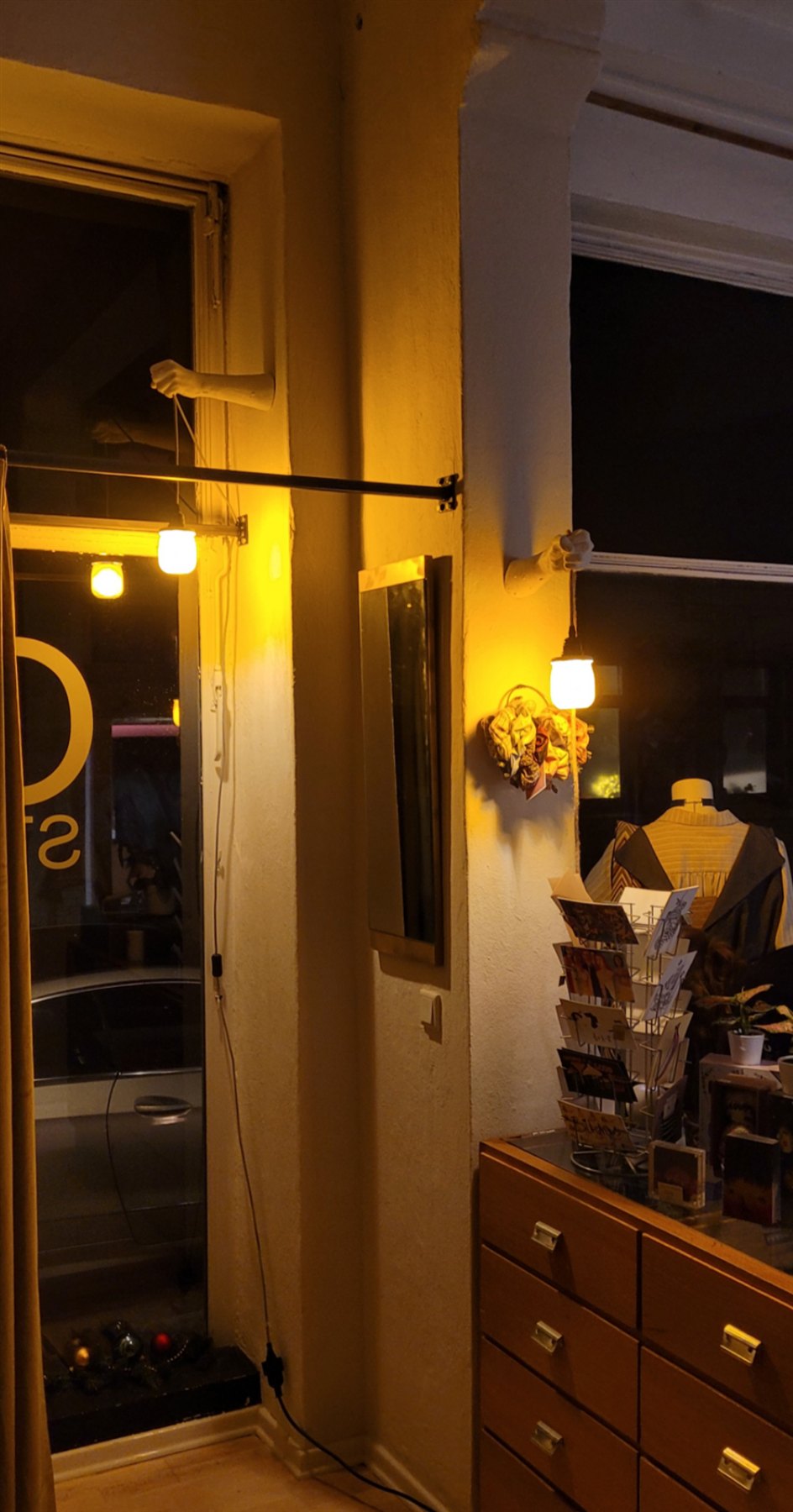 Einzelner Gipsarm hält eine Lampe an einem Fensterrahmen, bei Nacht
