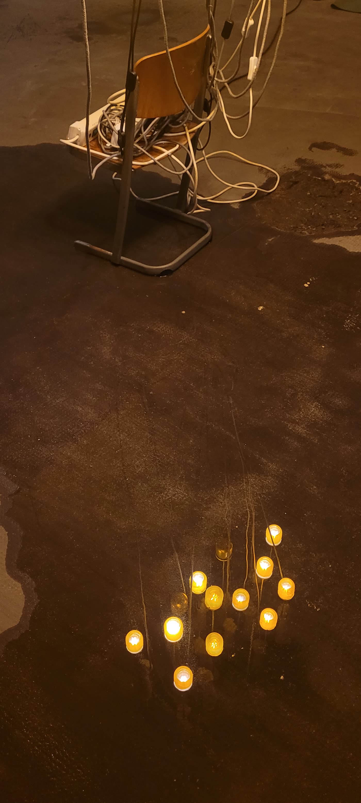 Blick von unten auf die glühenden Lampen zwischen Kabeln