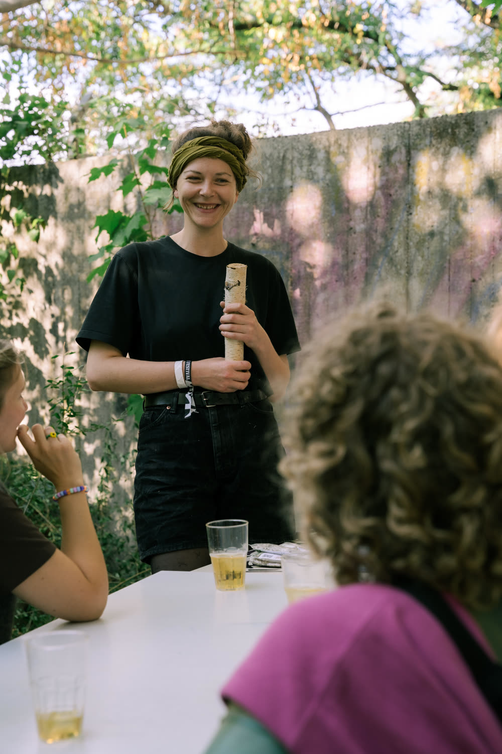 Franziska Füllgraf stellt lächelnd eine Porzellankapsel vor, im Gespräch mit Festivalbesucher:innen an einem Tisch
