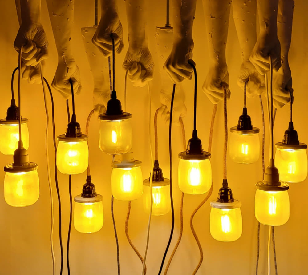 Dichtes Arrangement: viele Porzellanhände tragen glühende Marmeladenglas-Lampen